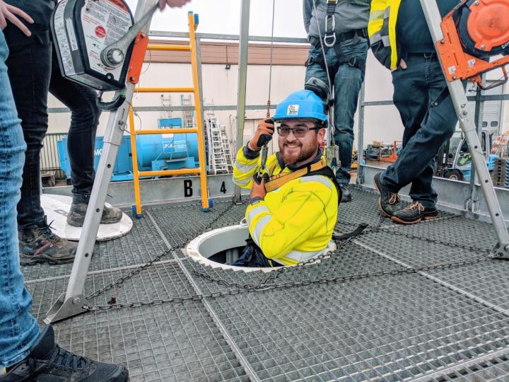 Een collega zakt veilig in een mangat van een besloten ruimte