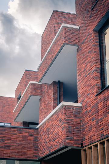 Een detailbeeld langs een zijgevel van een gebouw met rode gevels in De Boterton in Lier | DCA Bouw Een detailbeeld langs een zijgevel van een gebouw met rode gevels in De Boterton in Lier | DCA Bouw